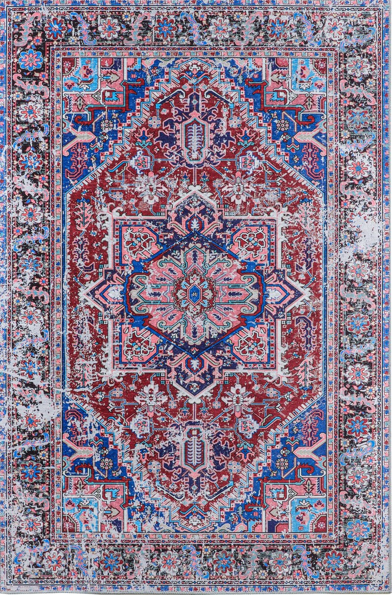 K&ouml;nnte beinhalten: Ein Vintage-Teppich mit einem abgenutzten, verblassten Look. Der Teppich hat ein zentrales Medaillon mit komplizierten geometrischen Mustern in Rosa-, Blau- und Gr&uuml;nt&ouml;nen. Der Rand des Teppichs ist dunkelblau mit einem sich wiederholenden Muster aus floralen Motiven.