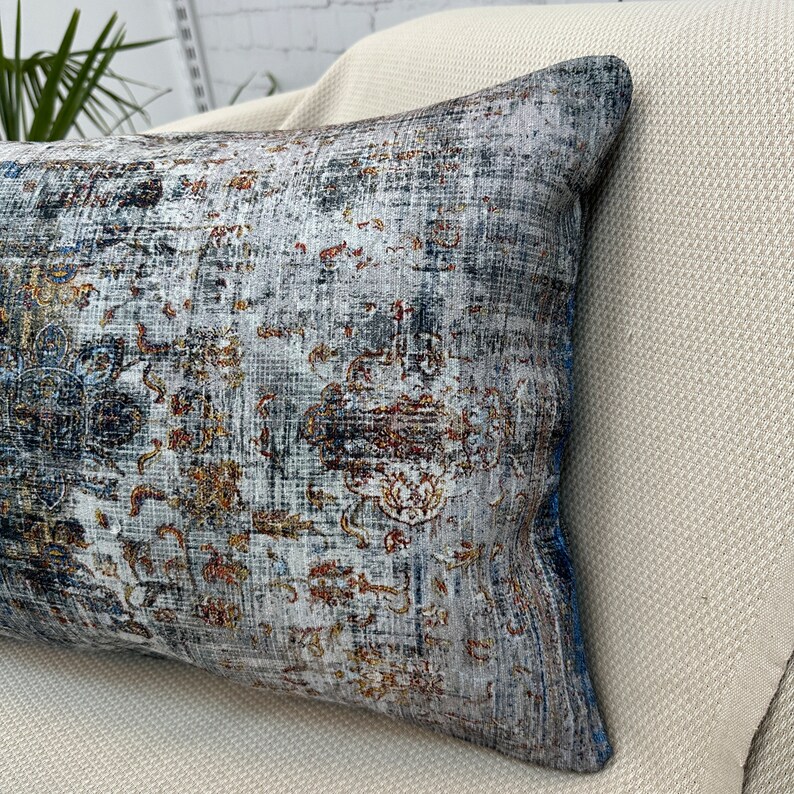 May include: A decorative throw pillow with a blue, gray, and gold patterned design. The pillow has a distressed look and is made of a soft, textured fabric.