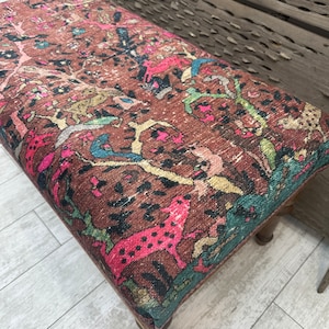 Peut inclure: Un ottoman &agrave; motifs color&eacute;s avec une base brune. Le tissu pr&eacute;sente un motif r&eacute;p&eacute;titif d'animaux et de plantes dans des tons de rose, bleu, vert et jaune.