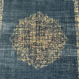 May include: A dark blue rug with a large, intricate, gold and cream colored medallion in the center. The rug has a distressed, vintage look.