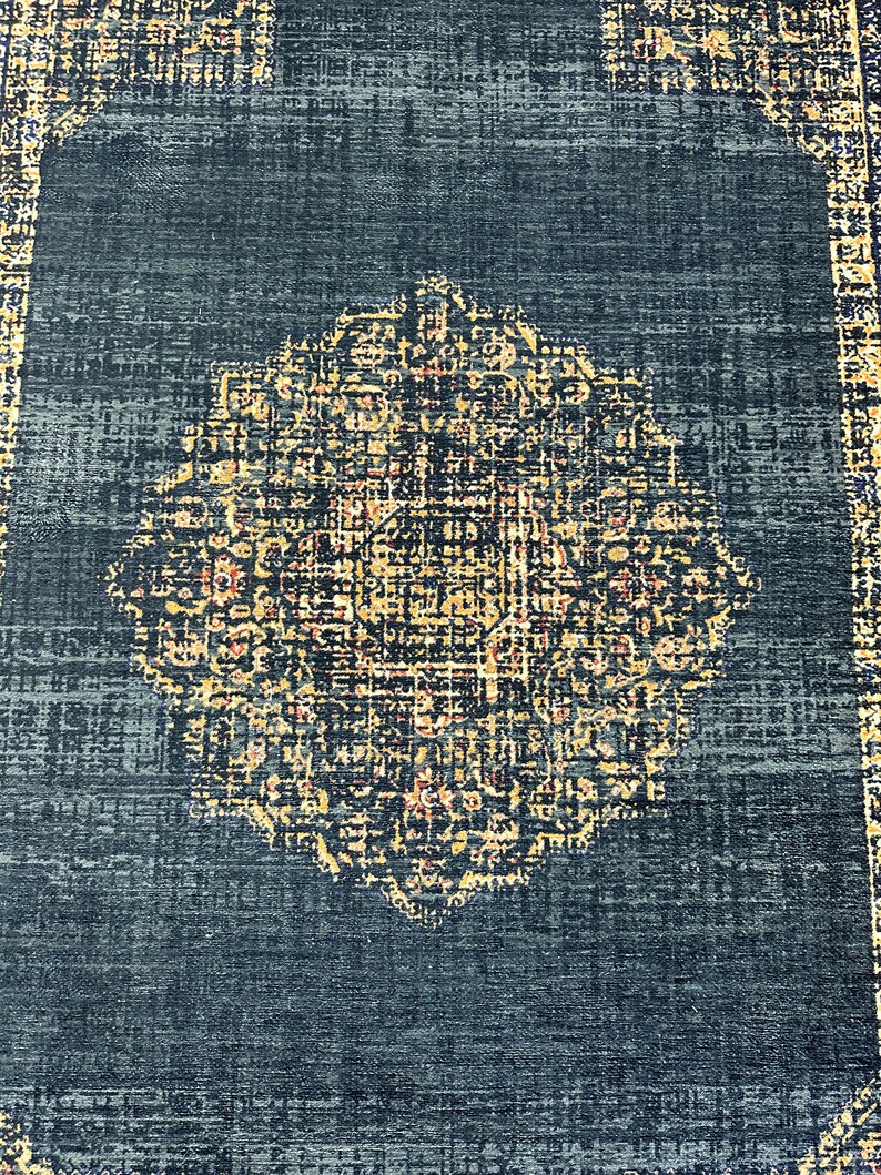May include: A dark blue rug with a large, intricate, gold and cream colored medallion in the center. The rug has a distressed, vintage look.