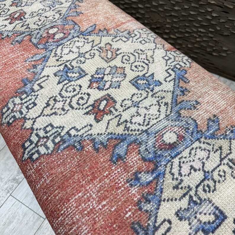 May include: Close-up of a red, white, and blue patterned rug with a geometric design. The rug has a distressed, vintage look.