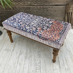 May include: A wooden bench with turned legs and a padded seat covered in a blue and white patterned fabric featuring a leopard print.