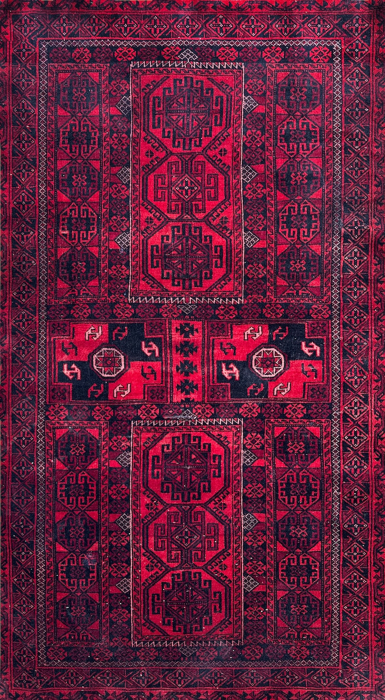 May include: A rectangular, hand-woven rug with a rich red background and intricate black geometric patterns. The design features repeating motifs and a detailed border, showcasing traditional craftsmanship. The rug's texture suggests a durable, high-quality material.
