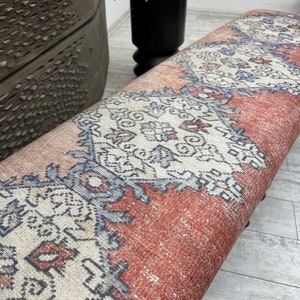 May include: A red, white, and blue patterned bench with a woven fabric top. The bench is made of wood and has a rustic look.