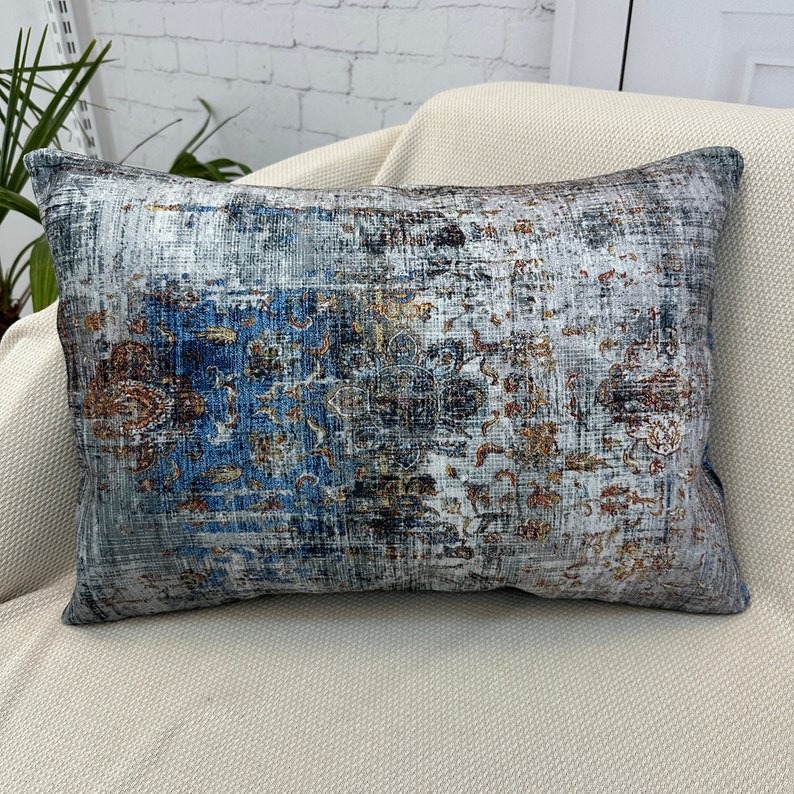 May include: A rectangular throw pillow with a blue, gray, and orange patterned design. The pillow has a distressed, vintage look.