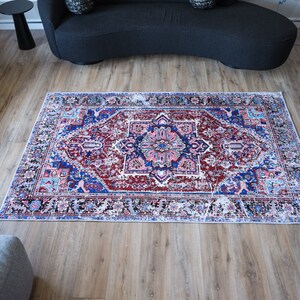 K&ouml;nnte beinhalten: Ein bunter Teppich mit traditionellem persischem Design in Rot-, Blau-, Rosa- und Wei&szlig;t&ouml;nen. Der Teppich hat ein zentrales Medaillon und komplizierte Blumenmuster.