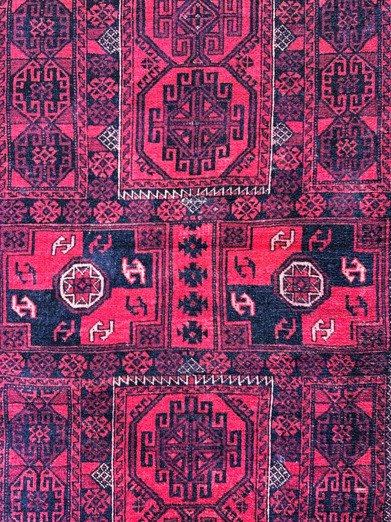 May include: A close-up of a red and black patterned rug. The rug features geometric designs, including octagonal shapes and repeating patterns. The color palette is dominated by deep red and black, with small white accents.