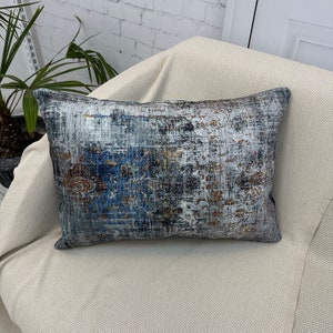 May include: A decorative throw pillow with a blue, gray, and brown abstract pattern. The pillow is made of a soft, textured fabric.