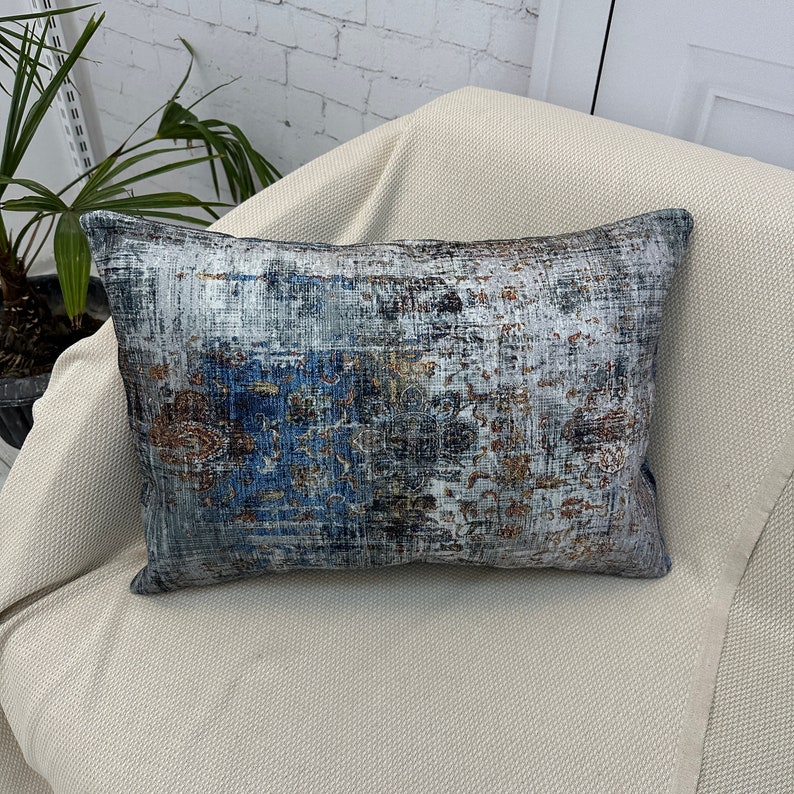 May include: A decorative throw pillow with a blue, gray, and brown abstract pattern. The pillow is made of a soft, textured fabric.