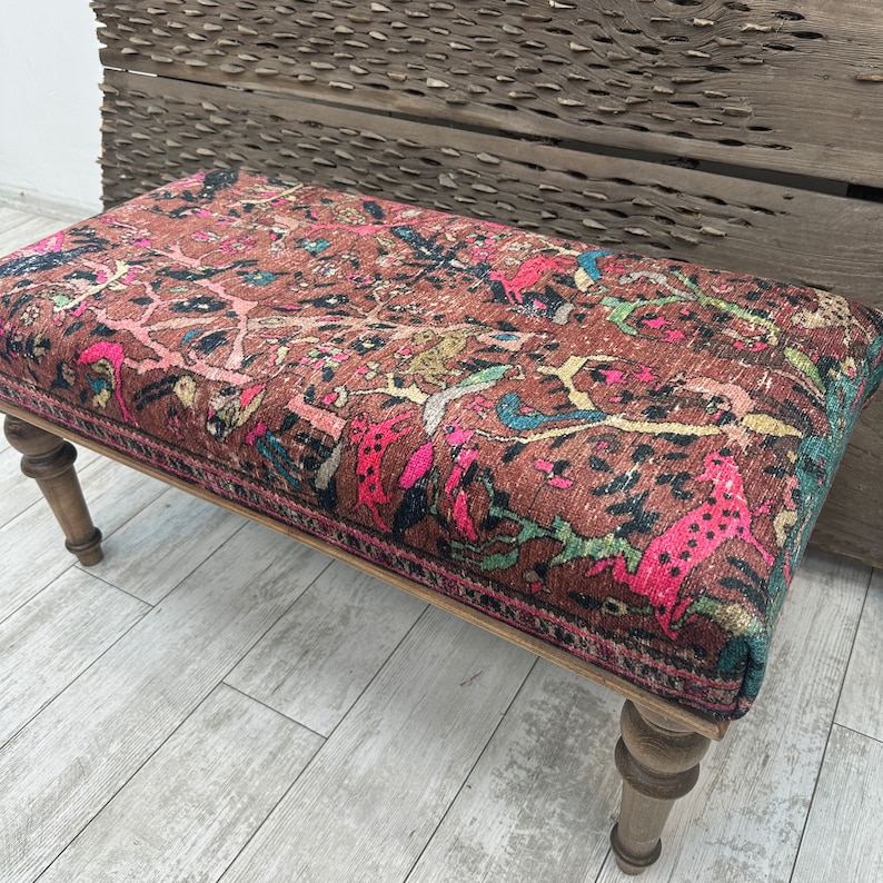 Peut inclure: Un banc en bois avec des pieds tourn&eacute;s et un dessus en tissu &agrave; motifs color&eacute;s. Le tissu pr&eacute;sente un motif floral avec des accents roses, verts et jaunes.