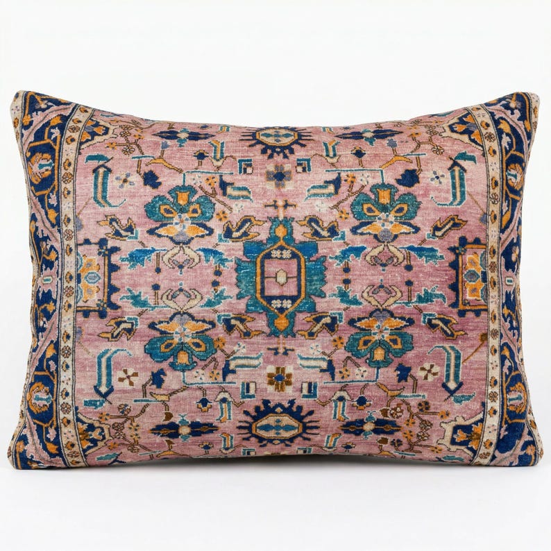 May include: Rectangular decorative pillow with a vintage rug design. The pillow features a dusty rose background with a detailed pattern in shades of blue, teal, and gold. The edges are bordered with a dark blue and gold design.