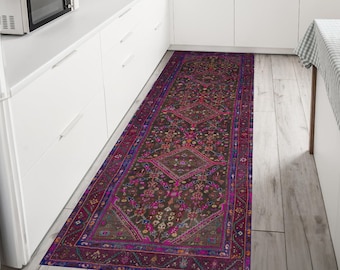 Puede incluir: Una alfombra larga y estrecha con un diseño persa tradicional. La alfombra tiene un fondo marrón oscuro con intrincados patrones en tonos de rosa, morado, azul y naranja. La alfombra es perfecta para agregar un toque de elegancia a cualquier habitación.