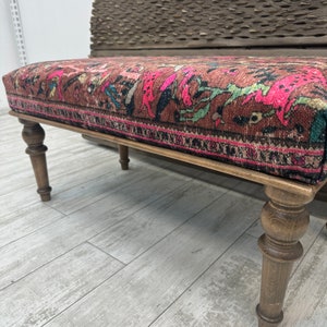 Peut inclure: Un banc en bois avec des pieds tourn&eacute;s et un si&egrave;ge en tissu &agrave; motifs color&eacute;s. Le tissu a un motif floral rose, rouge et bleu.