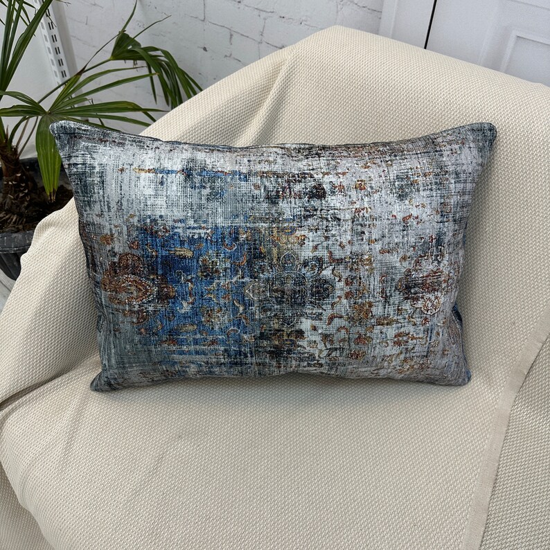 May include: A decorative throw pillow with a blue, gray, and gold patterned design. The pillow is made of a soft, textured fabric.