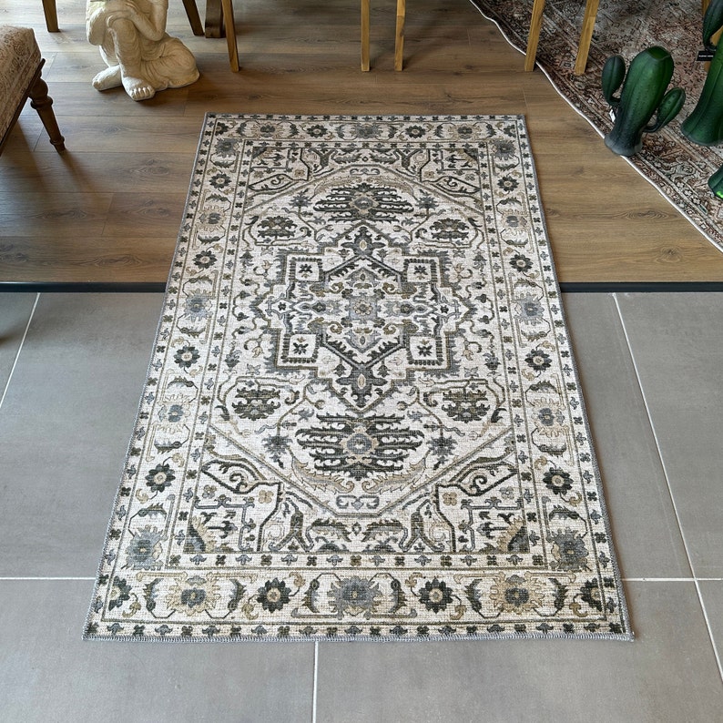 May include: A white rug with a beige and gray geometric pattern. The rug has a traditional design with intricate details.