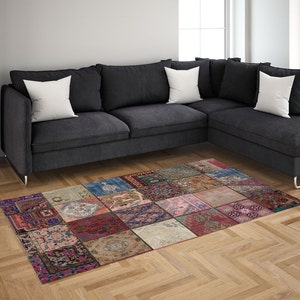 May include: A colorful patchwork rug with a variety of patterns and colors, including red, pink, blue, and green. The rug is made of different fabrics and textures, and it has a unique and eclectic style. The rug is placed in front of a gray sectional sofa with white pillows.