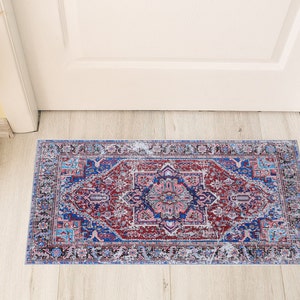 K&ouml;nnte beinhalten: Ein blauer und roter Teppich mit einem verblassten, Vintage-Look. Der Teppich hat ein traditionelles persisches Design mit komplizierten Details.