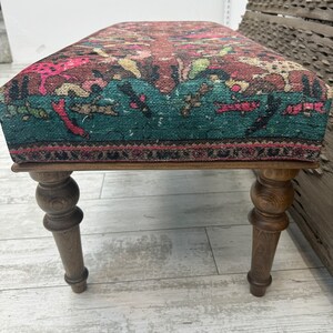 Peut inclure: Un banc en bois avec des pieds tourn&eacute;s et un si&egrave;ge en tissu &agrave; motifs color&eacute;s. Le tissu est de couleur turquoise, rose et marron.