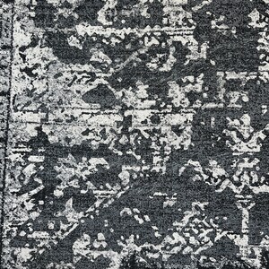 May include: A black and white area rug with a distressed, vintage look. The rug has a geometric pattern with a faded, worn appearance.