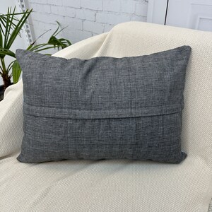 May include: A dark gray throw pillow with a zipper closure on the back.