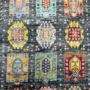 May include: A colorful rug with a repeating pattern of geometric shapes and floral designs. The rug has a dark gray background with bright colors like yellow, blue, red, and green.
