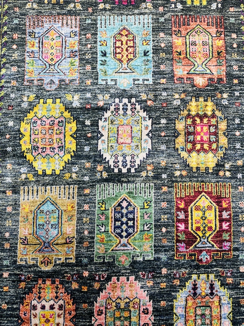 May include: A colorful rug with a repeating pattern of geometric shapes and floral designs. The rug has a dark gray background with bright colors like yellow, blue, red, and green.