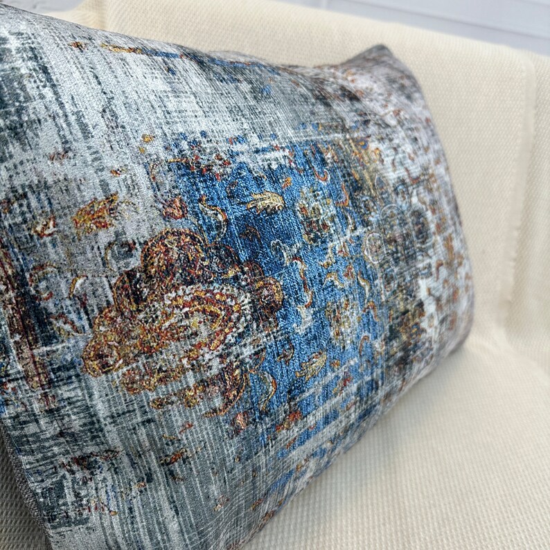 May include: A decorative throw pillow with a blue, gray, and gold patterned design. The pillow has a textured fabric and a subtle sheen.