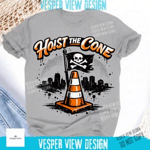 Peut inclure: T-shirt gris avec l'inscription "Hoist the Cone" en orange et blanc. Le motif comprend un drapeau pirate avec une t&ecirc;te de mort et des os crois&eacute;s, un c&ocirc;ne de signalisation orange et blanc et une silhouette de ville.