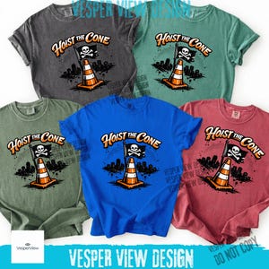 Peut inclure: Plusieurs t-shirts de couleurs vari&eacute;es : gris, vert, bleu, rouge et sarcelle. Chaque t-shirt affiche l'inscription "Hoist the Cone" avec un c&ocirc;ne de signalisation, un drapeau de pirate et un paysage urbain.