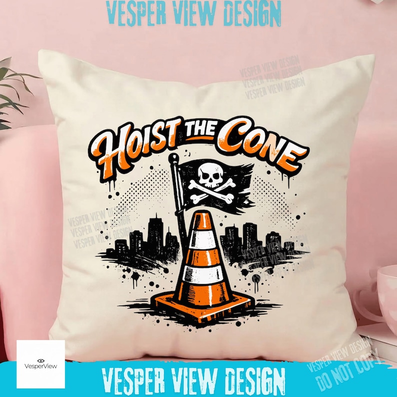 Peut inclure: Coussin cr&egrave;me avec un motif graphique repr&eacute;sentant un c&ocirc;ne de signalisation, un drapeau t&ecirc;te de mort et une ligne d'horizon urbaine. Le texte "Hoist the Cone" est en orange et noir. Le coussin est sur une surface rose.