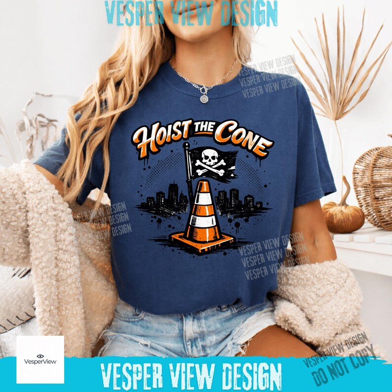 Peut inclure: T-shirt bleu marine avec l'inscription "Hoist the Cone" en orange et blanc. Le motif repr&eacute;sente un c&ocirc;ne de signalisation avec un drapeau t&ecirc;te de mort et une ligne d'horizon urbaine. C'est un v&ecirc;tement d&eacute;contract&eacute;.