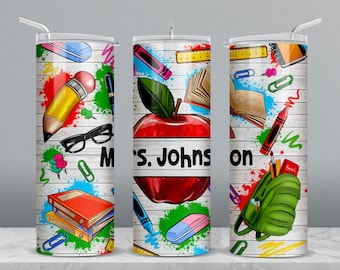 May include: Three stainless steel tumblers with a white woodgrain background and colorful school supplies, including a red apple, a pencil, a book, a backpack, and a ruler. The middle tumbler has the text "Mrs. Johnson" on it.