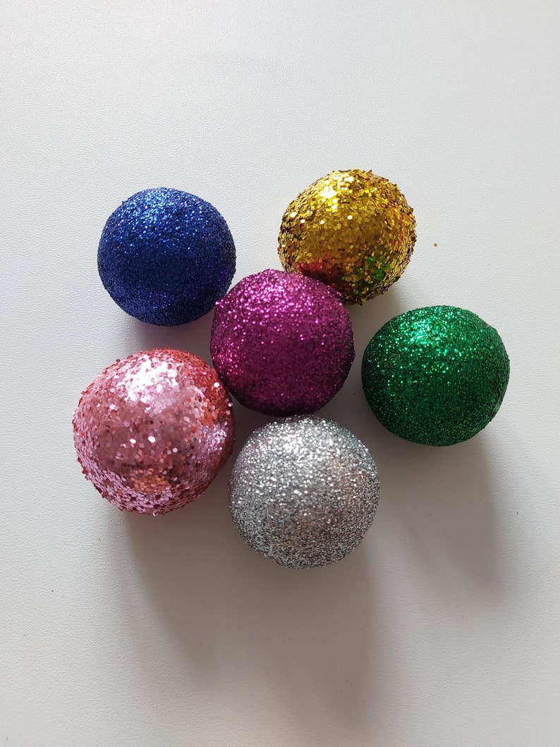 May include: Six sparkly Christmas ornaments in various colors, including pink, blue, green, silver, gold, and purple.