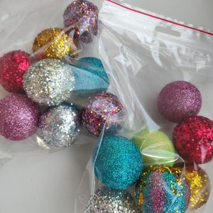 May include: A bag of colorful glitter balls in various colors including silver, pink, red, green, blue, and gold. The balls are in a clear plastic bag with a zipper.