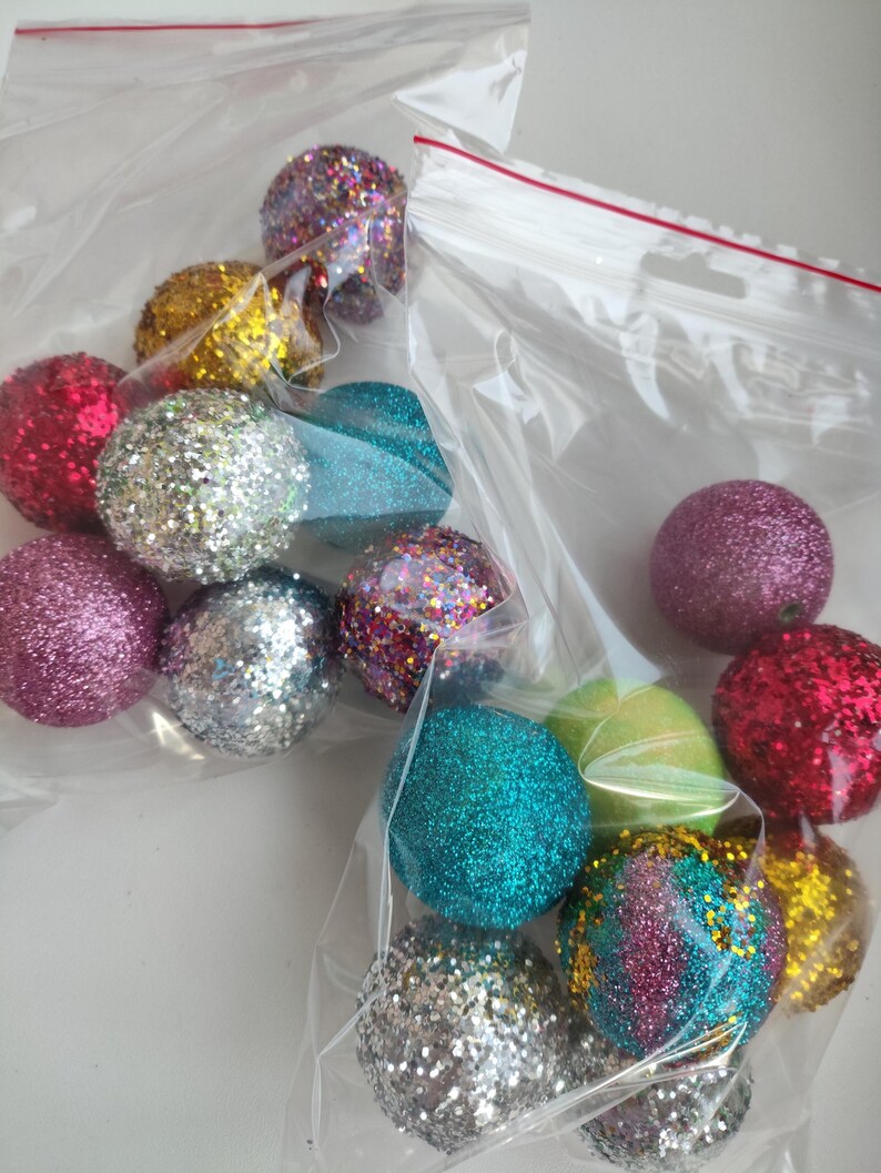 May include: A bag of colorful glitter balls in various colors including silver, pink, red, green, blue, and gold. The balls are in a clear plastic bag with a zipper.