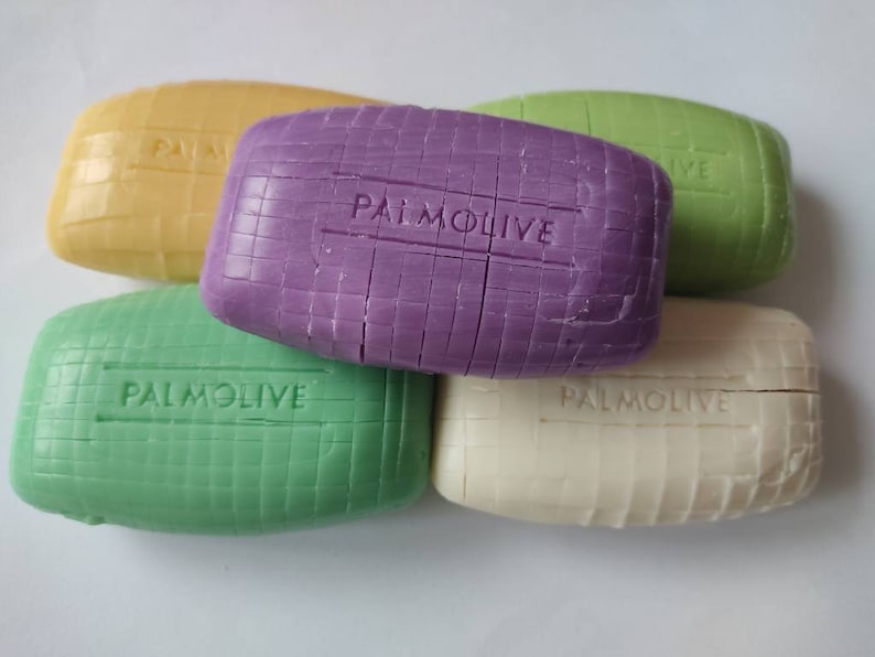 May include: Five bars of Palmolive soap, in various colours, including yellow, purple, green, and white. Each bar has the word "Palmolive" embossed on it.
