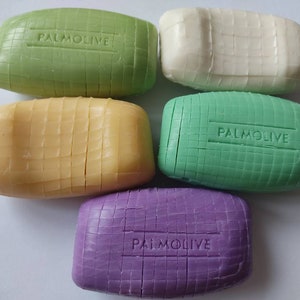 May include: Five bars of Palmolive soap in different colours: green, white, yellow, green, and purple. Each bar has a raised grid pattern and the word "Palmolive" embossed on the top.