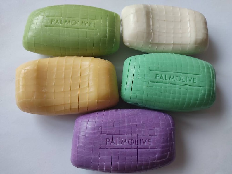 May include: Five bars of Palmolive soap in different colours: green, white, yellow, green, and purple. Each bar has a raised grid pattern and the word "Palmolive" embossed on the top.