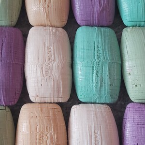 May include: A collection of ten bars of Palmolive soap. The bars are arranged in two rows of five. The bars are in various colours, including green, purple, and white. Each bar has the Palmolive logo embossed on it.
