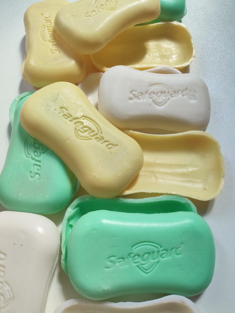 May include: A close-up of several bars of soap, some are green, some are yellow, and some are white. All of the bars have the word "Safeguard" printed on them.