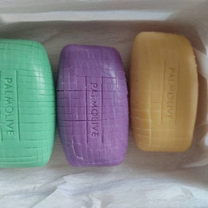 May include: Three bars of soap, one green, one purple, and one yellow, all with the word "PALMOLIVE" printed on them.