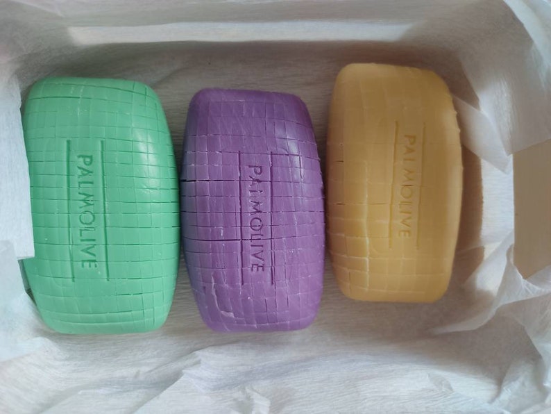 May include: Three bars of soap, one green, one purple, and one yellow, all with the word "PALMOLIVE" printed on them.