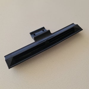 May include: Black plastic vent with a series of horizontal slots and two small holes on the top.