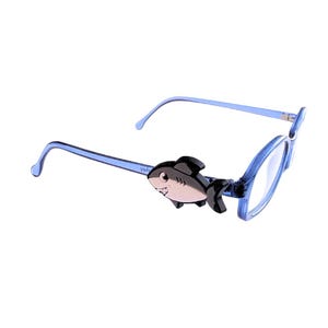 May include: Blue eyeglasses with a shark accent on the temples. The shark is black and silver, adding a playful touch to the frames. The lenses are clear, and the arms are a light blue.