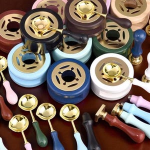 Puede incluir: Un surtido de juegos de sellos de lacre, con varios colores y diseños. Los juegos incluyen hornos para derretir cera con cucharones dorados y sellos con mangos de madera en tonos rosa, azul, verde y marrón. Ideal para manualidades y papelería.