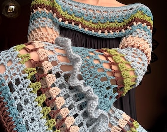 Op de afbeelding: Een handgemaakte gehaakte top in tinten blauw, groen, bruin en beige. Het open ontwerp heeft een gerimpelde rand en lange mouwen. Een uniek stuk draagbare kunst.