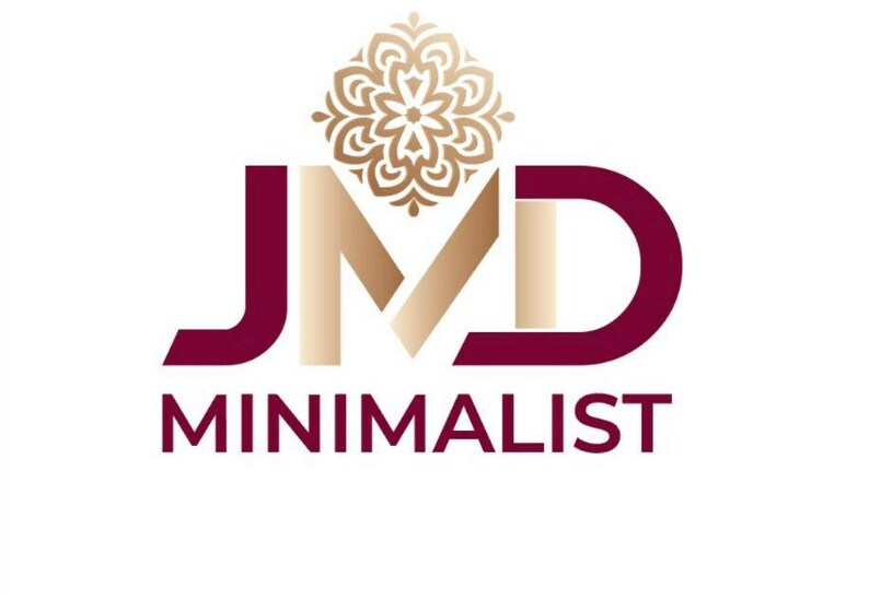 Puede incluir: Un logotipo que presenta las letras JMD en un esquema de color degradado granate y dorado. Sobre la letra M hay un icono de mandala floral dorado. Debajo de las letras JMD, la palabra MINIMALIST est&aacute; impresa en letras may&uacute;sculas granates.