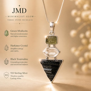 Puede incluir: Un collar de plata con tres piedras apiladas: una moldavita verde rectangular, un cristal Herkimer hexagonal transparente y una turmalina negra triangular. El texto JMD MINIMALIST GLOW THREE STONE NECKLACE es visible junto a las descripciones de las piedras.