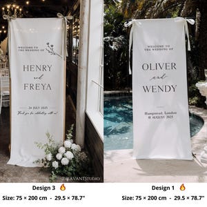 May include: Two white wedding welcome banners, each 29.5 x 78.7 inches, with text. One reads "HENRY and FREYA" and the other "OLIVER and WENDY". Both banners include wedding dates and locations. Floral accents and tied top details.
